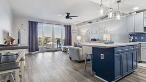 Een moderne keuken met een centraal eiland, een eethoek met een tafel en stoelen, en een balkon met uitzicht.
