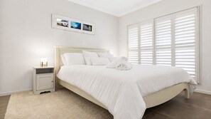 A bedroom with a bed, nightstand, and a window with blinds.
