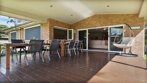 Un patio al aire libre con pared de ladrillo, mesa de madera con sillas y una silla colgante.