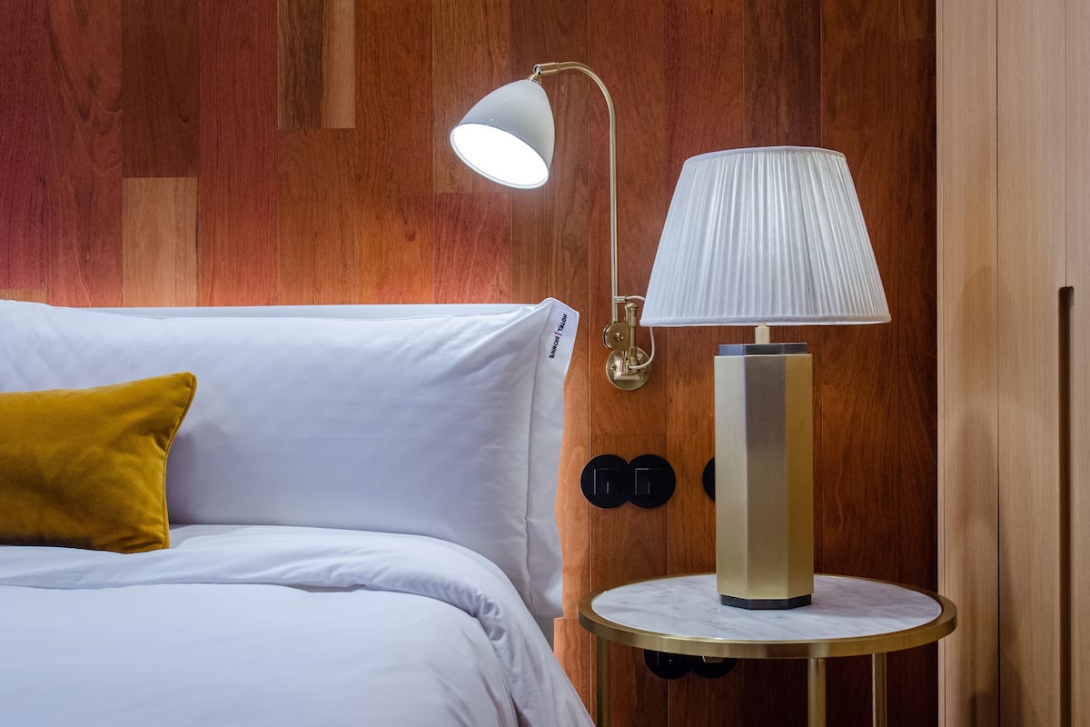 Ein Hotelzimmer mit einem Bett, einem runden Tisch mit einer Lampe und einer Holzwand.