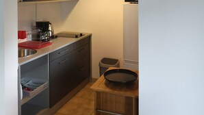 Una cocina compacta con microondas, pileta y un reloj en la pared.