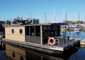 Ein hölzernes Boot mit Deck, Fenstern und einem Rettungsring.