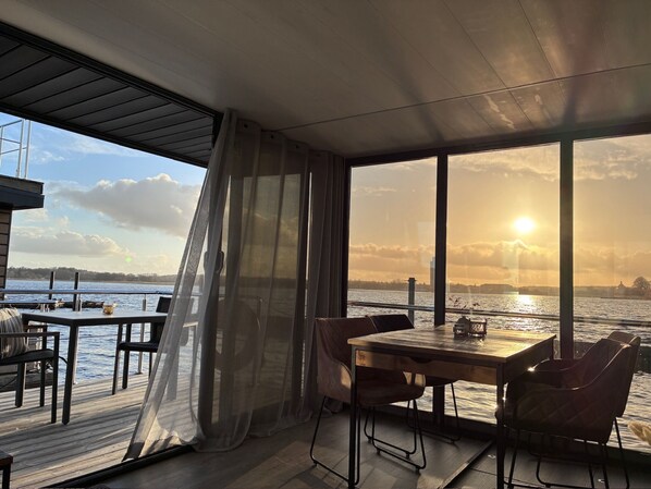 Ein Zimmer mit großem Fenster und Blick auf ein Gewässer, einem Holztisch und Stühle.