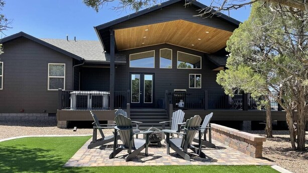 A modern house with a covered patio, outdoor seating, and a well-maintained lawn. - Gorgeous Lazy Bear Inn (Show Low)