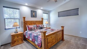 A bedroom with a wooden bed, two bedside tables, a ceiling fan, and large windows. - Gorgeous Lazy Bear Inn (Show Low)