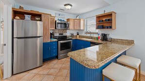 Una cocina moderna con gabinetes azules, electrodomésticos de acero inoxidable y una encimera de granito.