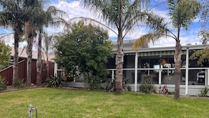 A residential property with a well-maintained lawn, a wooden fence, and a house with a balcony. - Leisure escape (Rosebud)