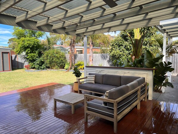 Relax in a serene outdoor space with a sofa and table, surrounded by lush greenery.