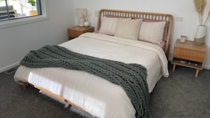 A bedroom with a bed, a bedside table, a lamp, and a window. - Leisure escape (Rosebud)