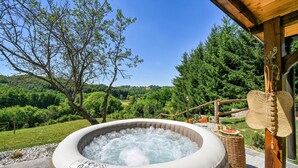Un bain à remous offrant une vue sur un paysage verdoyant et luxuriant, ainsi que sur une structure en bois.