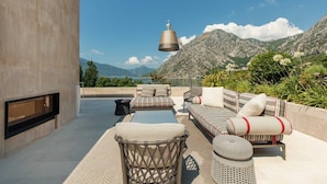 Une terrasse sur le toit aménagée avec un ensemble de canapés, une table et une lampe suspendue.