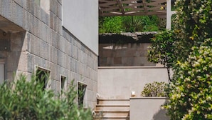 Un edificio in pietra dal design moderno, con una scalinata che conduce a un'area coperta con elementi verdi.