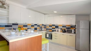 Een moderne keuken met witte kasten, een centraal eiland, een magnetron en een koelkast.