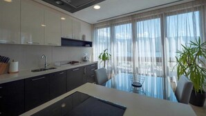 Una cuina moderna amb armaris foscos, una illa gran i zona de dinar amb vistes.