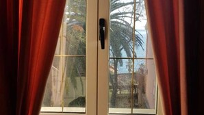 Een raam met uitzicht op palmbomen en een heldere lucht.