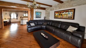 A spacious living room with a large L-shaped black leather sofa, a wooden coffee table, and a chandelier. - Classic  Estate  Villa (Kotor)