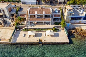 A multi-story building with a tiled roof, a swimming pool, and outdoor seating. - Moonlight Beach Villa (Tivat)
