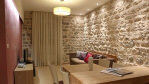 Ein Essbereich mit einer Steinsäule, einem Holztisch und einer Couch mit Kissen.