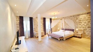 Ein Schlafzimmer mit Himmelbett, Steinwänden und Holzboden.