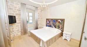 A bedroom with a large bed, a window with curtains, a painting on the wall, and a chandelier. - Stone House Seafront Villa (Kotor)
