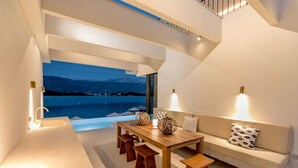 Un interior modern amb zona de menjador, un sofà i vistes a un cos d'aigua.