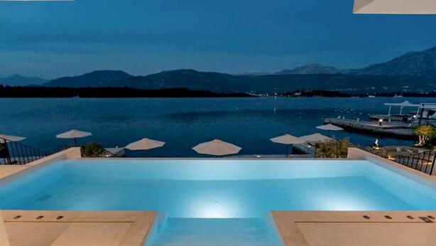 Una piscina amb vista a un llac i muntanyes al capvespre.