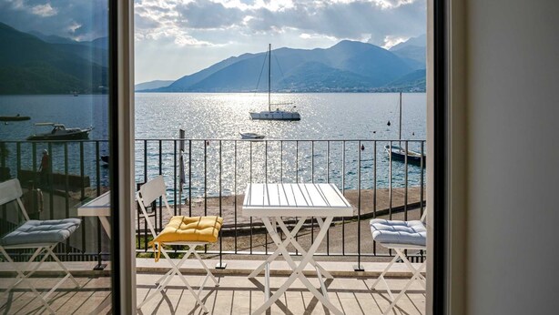 Un balcone con vista su un lago, barche e montagne.