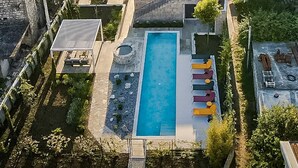 Un quartiere residenziale con piscina, edifici in pietra e vista sul mare.