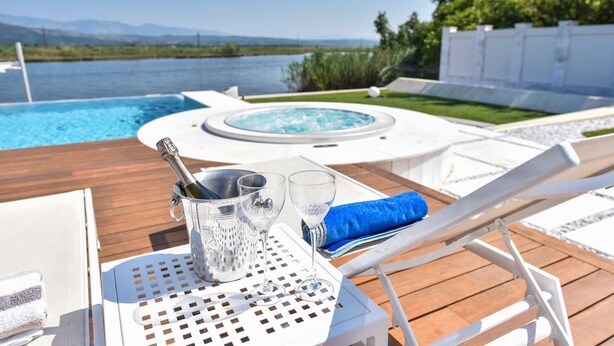 A poolside area with a hot tub, lounge chairs, and a table with a bottle of champagne and glasses. - Dulcinea  Dream  Villa (Ulcinj)