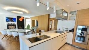 A modern kitchen with a central island, stainless steel appliances, and a dining area with white chairs. - Dulcinea  Dream  Villa (Ulcinj)