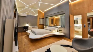A modern bedroom with a curved bed, a desk, and a bathroom visible through a glass door. - Dulcinea  Dream  Villa (Ulcinj)