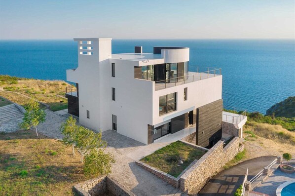 Ein modernes, zweistöckiges Haus mit Pool, mit Blick auf ein Gewässer.