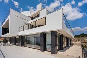 A modern two-story house with large glass windows and a balcony.