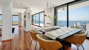 Un comedor moderno con una mesa grande, sillas y vista al mar.