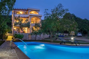 Une maison à deux étages avec une piscine, des murs en pierre et un balcon.