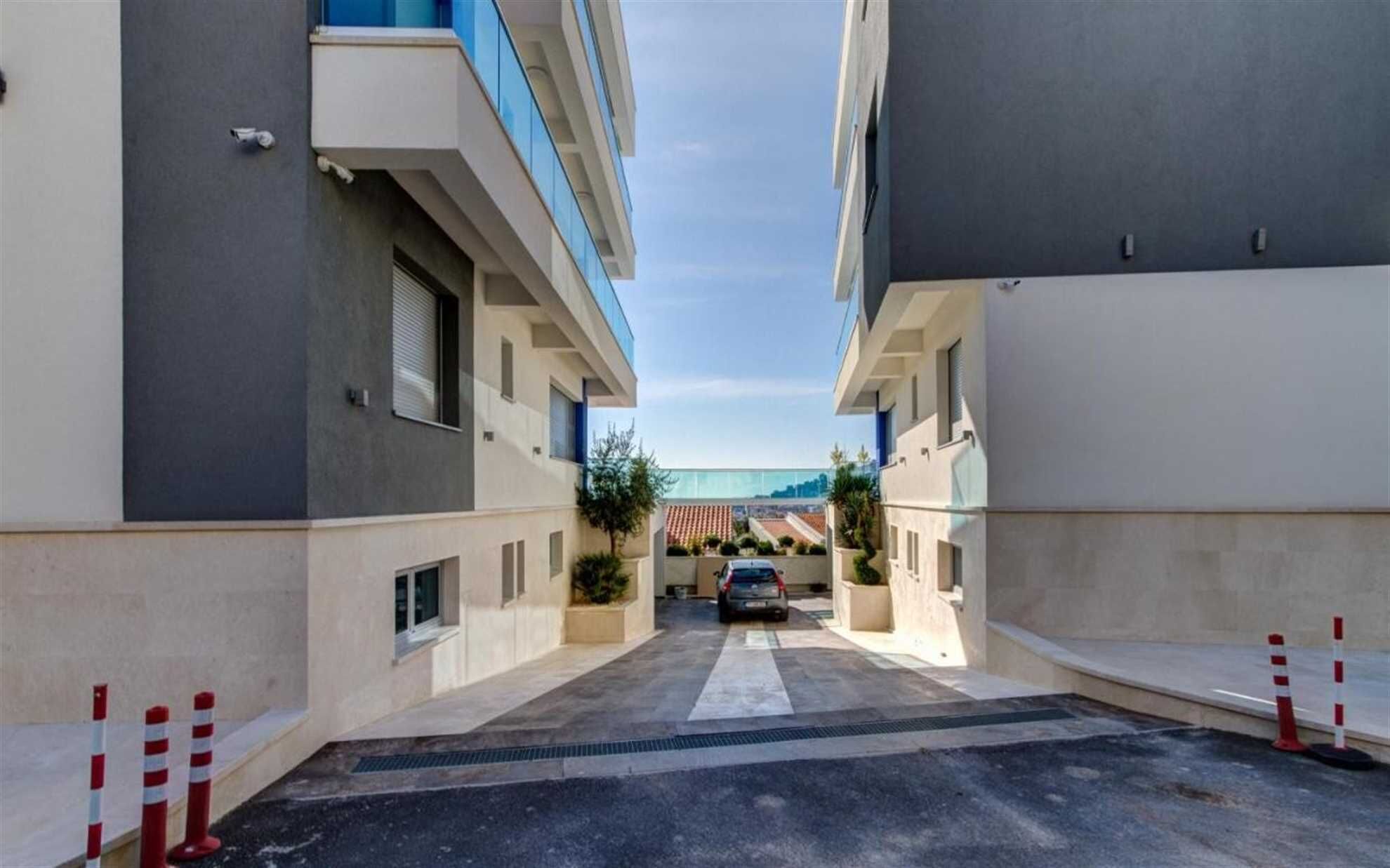 A narrow driveway leading to a building with a car parked in the middle.