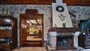 A rustic interior with a stone fireplace, wooden bookshelves, and a stone wall. - Royal Villa Ana - 2 Bedroom Villa (Cetinje)