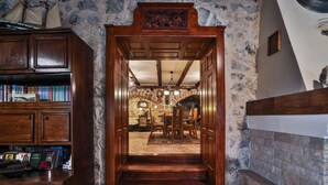 A wooden door leading to a stone-walled room with a fireplace, a wooden table, and chairs. - Royal Villa Ana - 2 Bedroom Villa (Cetinje)