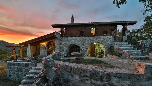 A stone building with a covered patio, outdoor seating, and a stone staircase leading up to the entrance. - Royal Villa Ana - 2 Bedroom Villa (Cetinje)