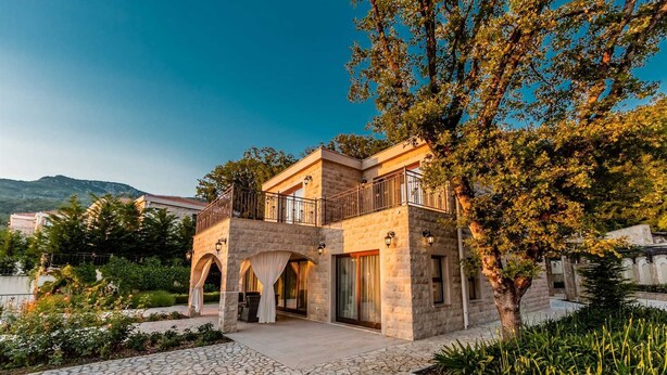 A two-story stone building with a balcony, arched doorways, and a stone pathway leading to the entrance. - Oak Leaf Residence Villa 1 (Budva)