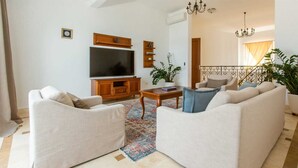 A living room with two sofas, a coffee table, a TV, and a staircase. - Oak Leaf Residence Villa 1 (Budva)