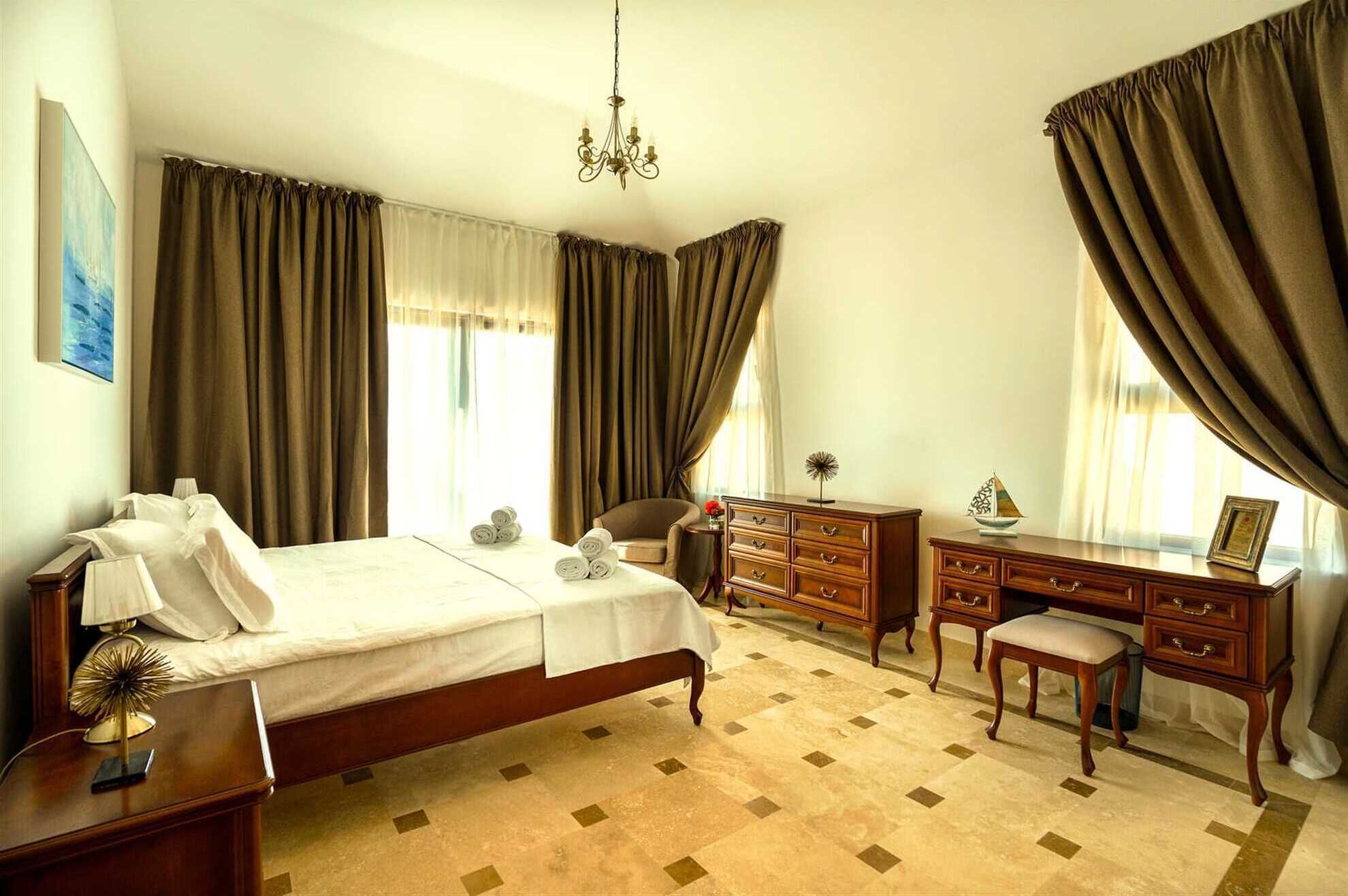 Una camera d'albergo con un letto, una scrivania, una sedia, una cassettiera e un lampadario.