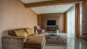 Una sala de estar moderna con un sofá seccional, un sillón rosa, un televisor de pantalla plana y una chimenea.