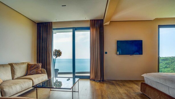 Habitación de hotel moderna con un amplio ventanal corredero que da a un balcón con vistas al mar.