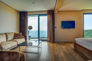 Quarto de hotel moderno com uma grande porta de vidro deslizante que dá para uma varanda com vista para o mar.