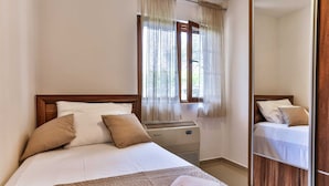 Een slaapkamer met een bed, een verwarming en een raam met gordijnen.