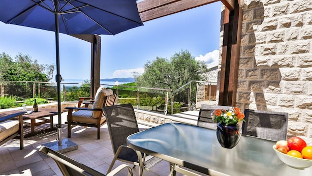 Een terras buiten met een tafel, stoelen en een blauwe parasol.