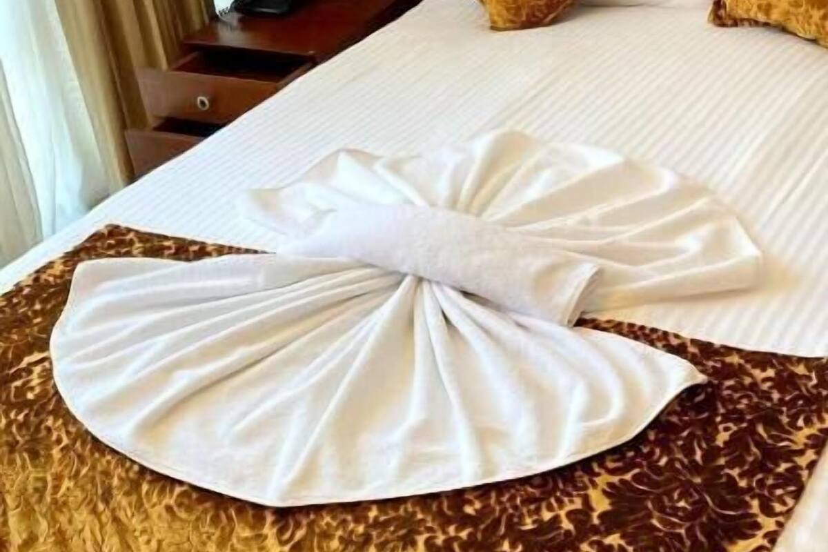 Un letto rifatto con cura, un grande cuscino a forma di fiocco e una coperta a motivi.