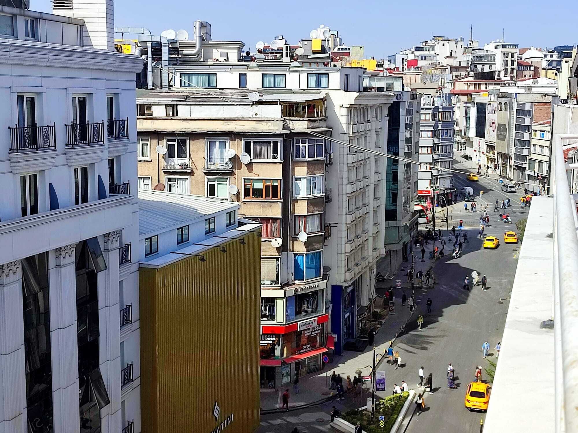 A multi-story urban street with various buildings, including a prominent building with a gold facade.