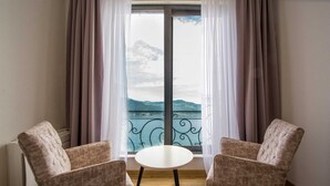 Une pièce avec deux fauteuils placés face à une grande fenêtre donnant sur un lac et des montagnes.